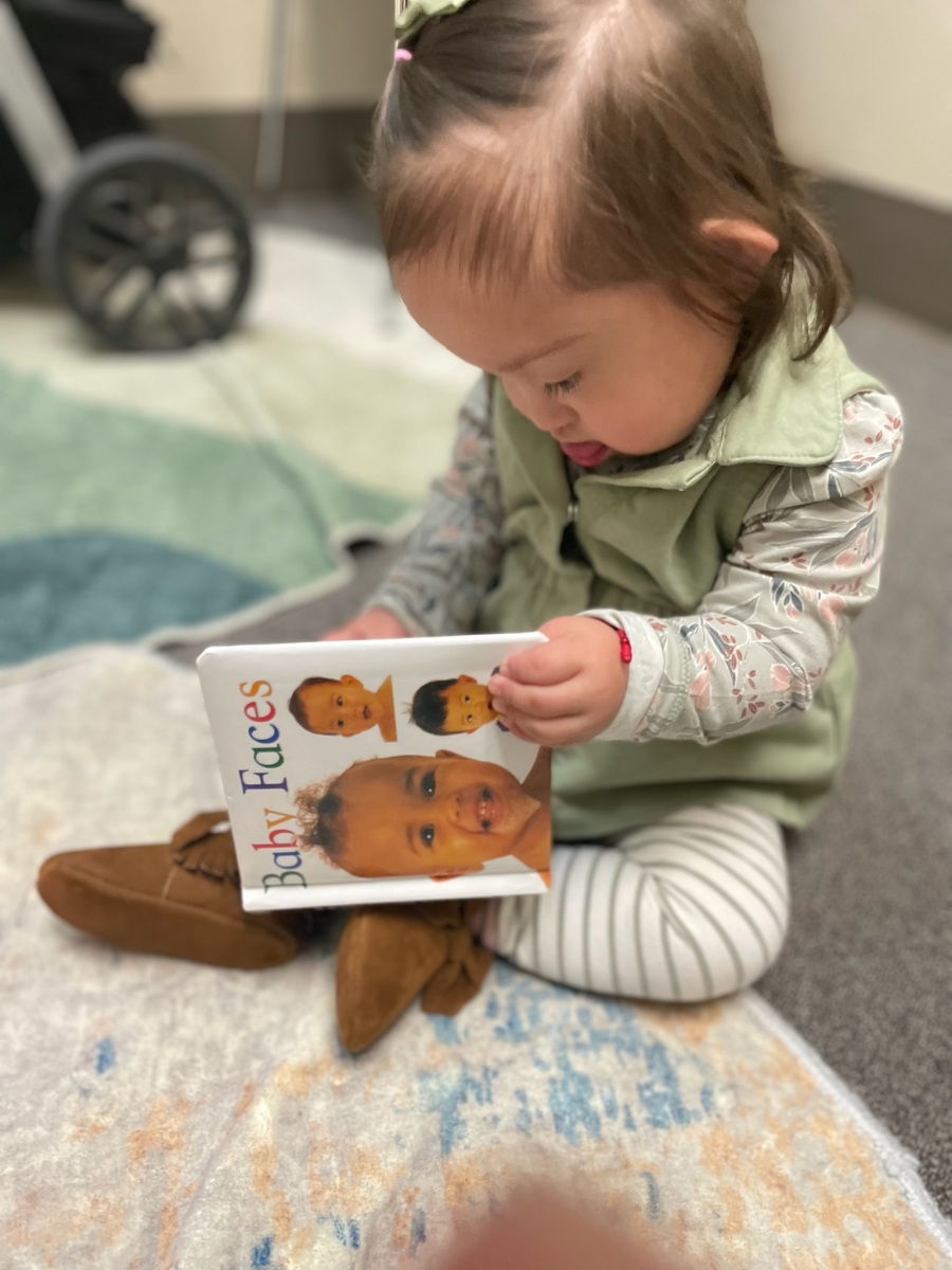 Little girl sitting cross legged on the floor looking through a picture book