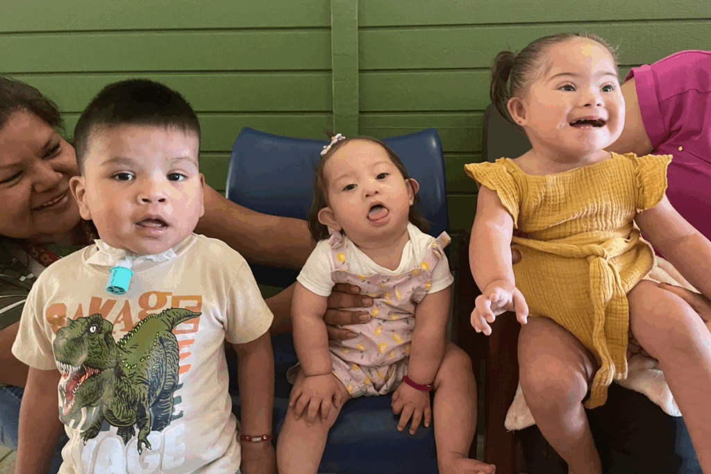 Three little kids sitting together smiling at the camera